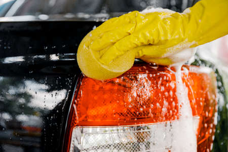 A woman's hand with a yellow sponge for washing, washing a car.の写真素材