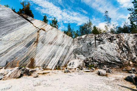 The rock has carved an untreated surface of white and gray marble in a natural environment. The quarry texture of blue marbleの写真素材