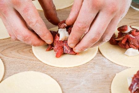 A man is holding a khinkali in close-up. Cook in the kitchen. The process of preparing a national...
