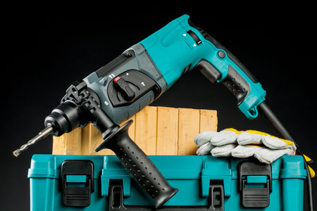 Drill and protective gloves on a black background.