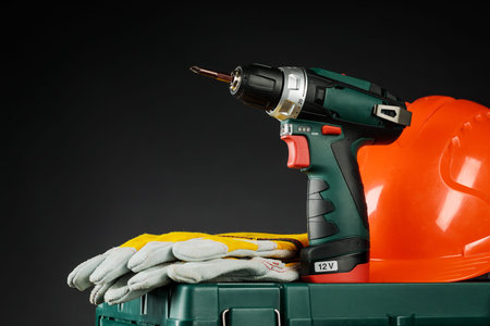 Drill and protective gloves on a black background.