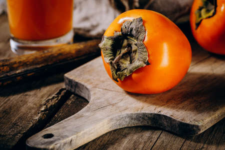 A group of ripe orange persimmon fruits.Persimmon fruits on a wooden board, rustic background.の写真素材