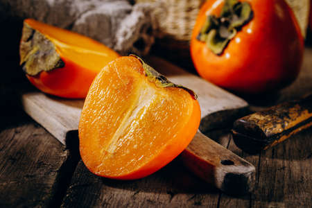 A group of ripe orange persimmon fruits.Persimmon fruits on a wooden board, rustic background.の写真素材