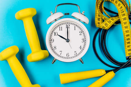 Time for workout clock and dumbbell with colorful blue background.の写真素材