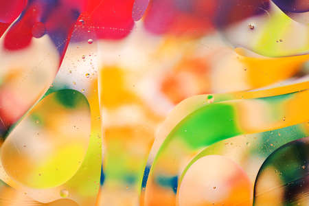 Close-up of the movement of oil droplets on the water surface. Colorful abstract macro background of oil drops on the water surfaceの写真素材