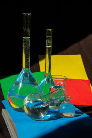 Flasks with liquid on a colorful background with light on it.の写真素材