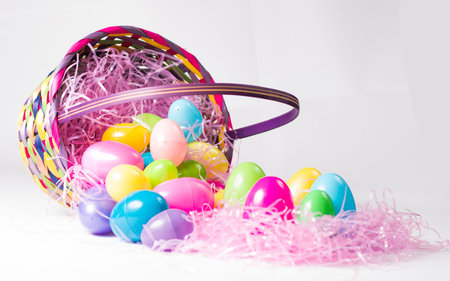 Dumped Easter basket full of colorful eggs on pink grass