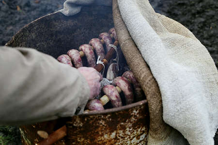 Hand puts sausages into homemade smokehouseの写真素材