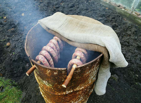Smoked sausages in home made smokehouse in garden.の写真素材