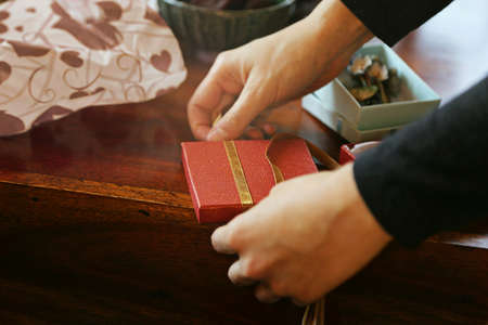 Wrapping red gift with ribbon on wooden tableの写真素材