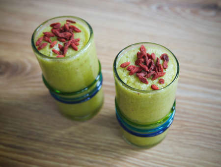 Healthy drink green smoothies with red goji berries on topの写真素材