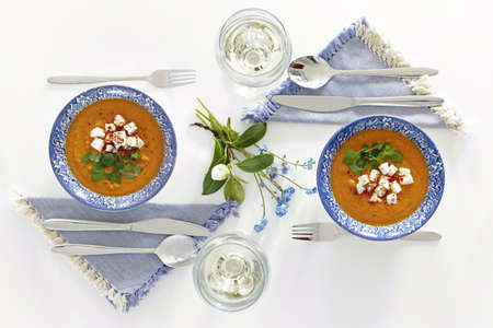 Plates and glasses, romantic dinner for two. Homey atmosphere clean white table. Top view. Orange soupの写真素材