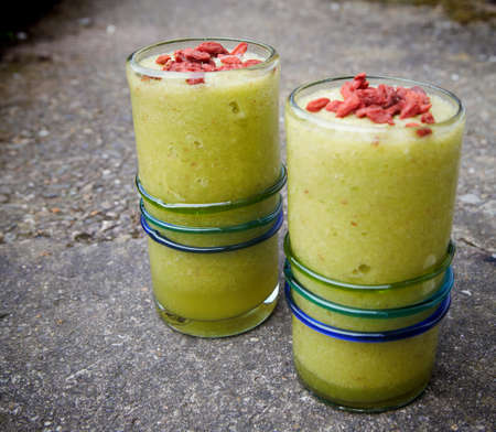 Healthy drink green smoothies with red goji berries on topの写真素材