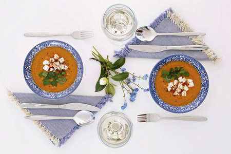 Plates and glasses, romantic dinner for two. Homey atmosphere clean white table. Top view. Orange soupの写真素材