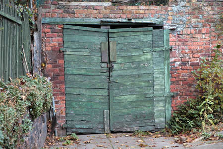 Vintage wooden garage doors. Green old timber garage gate on red brick wall.の写真素材
