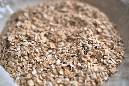 dry rolled organic oats in white plate. Deep blur and bokehの写真素材