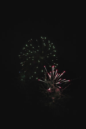 Shiny natural fireworks on dark black sky background with a little smoke