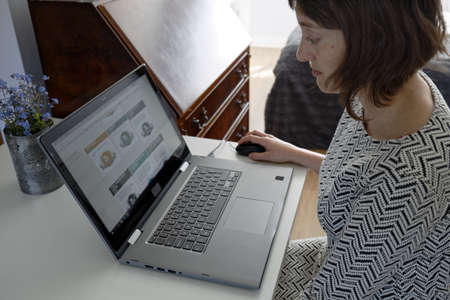 Young woman working in old office on laptop computer. Girl uses mouse to navigate through internet