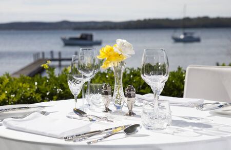 Table set up for lunch in an upmarket restaurant overlooking waterの写真素材