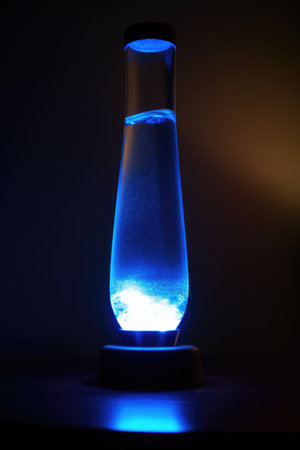 Blue lava lamp on table in dark room at night, created using generative ai technology. Retro, psychedelic, relaxation and interior decoration lamp concept digitally generated image.の素材