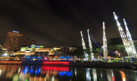 SINGAPORE - MARCH 02: Night shot of Clarke Quay at late evening and night over river in Singapore. Illuminated building of popular meeting place. At left side in background are hotels. In restaurants at promenade are many people.のeditorial素材