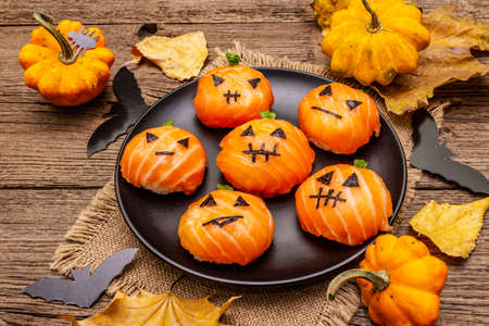 Funny Halloween Sushi Pumpkins Jack o Lantern, Sushi Monsters. Temari sushi, sushi balls. Healthy food for kids. Autumn leaves, bats, old wooden boards background, close upの写真素材