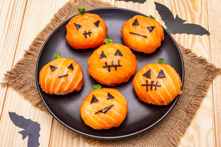 Funny Halloween Sushi Pumpkins Jack o Lantern, Sushi Monsters. Temari sushi, sushi balls. Healthy food for kids. Bats, sackcloth, wooden boards background, close upの写真素材