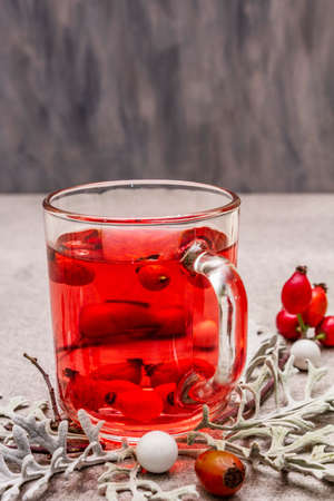 Hot dog-rose tea. Winter drink for good mood with fresh berries, leaves and candies. Stone concrete background, copy space, close upの写真素材