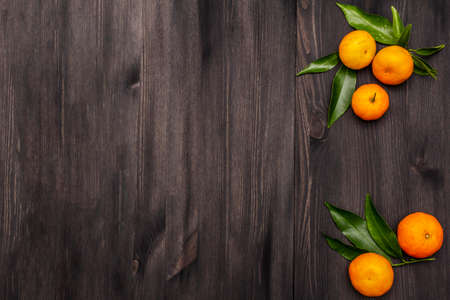 Fresh ripe tangerines with leaves. New Year or Christmas wooden background. Festive good mood concept, copy space, top viewの写真素材