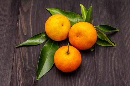 Fresh ripe tangerines with leaves. New Year or Christmas wooden background. Festive good mood concept, close up, top viewの写真素材
