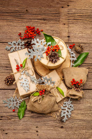 Christmas zero waste concept. New Year eco friendly packaging. Festive boxes in craft paper and sacks with different organic decorations. Old wooden boards background, top viewの写真素材