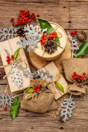 Christmas zero waste concept. New Year eco friendly packaging. Festive boxes in craft paper and sacks with different organic decorations. Old wooden boards background, top view, close upの写真素材