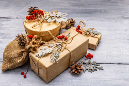 Christmas zero waste concept. New Year eco friendly packaging. Festive boxes in craft paper and sacks with different organic decorations. Wooden boards background, close upの写真素材