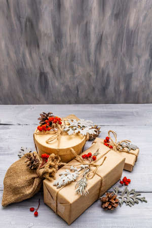 Christmas zero waste concept. New Year eco friendly packaging. Festive boxes in craft paper and sacks with different organic decorations. Wooden boards background, copy spaceの写真素材