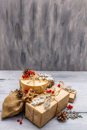 Christmas zero waste concept. New Year eco friendly packaging. Festive boxes in craft paper and sacks with different organic decorations. Wooden boards background, copy spaceの写真素材