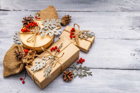 Christmas zero waste concept. New Year eco friendly packaging. Festive boxes in craft paper and sacks with different organic decorations. Wooden boards background, copy spaceの写真素材