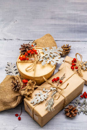 Christmas zero waste concept. New Year eco friendly packaging. Festive boxes in craft paper and sacks with different organic decorations. Wooden boards background, copy space, close upの写真素材