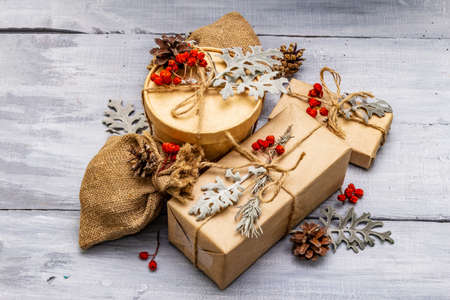 Christmas zero waste concept. New Year eco friendly packaging. Festive boxes in craft paper and sacks with different organic decorations. Wooden boards background, close upの写真素材