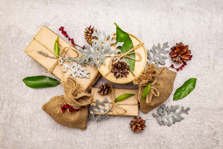 Christmas zero waste concept. New Year eco friendly packaging. Festive boxes in craft paper and sacks with different organic decorations. Stone concrete background, copy space, top viewの写真素材