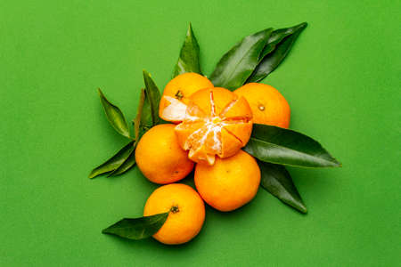 Ripe tangerines with leaves. Fresh fruits isolated on green background, copy space, top viewの写真素材