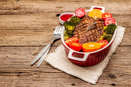 Baked duck breast on the bone with vegetables and sauce. Traditional healthy food concept. Vintage wooden boards background, copy space, close upの写真素材