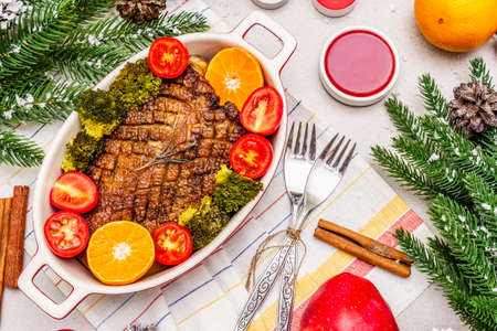 Baked duck breast on the bone with vegetables and sauce. Christmas dinner concept, New Year table setting. Stone concrete background, top view, close upの写真素材