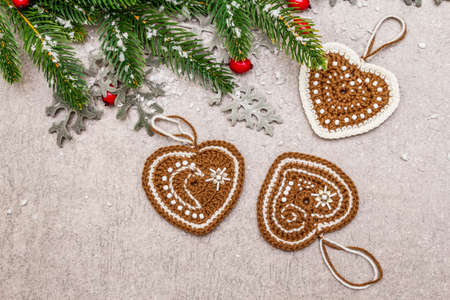 Christmas background. New Year fir tree, dog rose, fresh leaves, crocheted ginger cookies hearts and artificial snow. Stone concrete backdrop, top view, close upの写真素材
