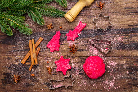 Cooking red ginger cookies. Traditional Christmas pastries. Festive culinary background. Fir tree, spices, cookie cutters, raw dough, rolling pin, wooden boards, top view, close upの写真素材