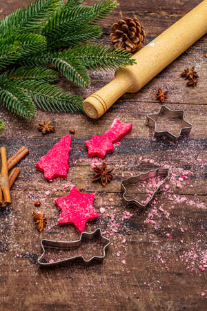 Cooking red ginger cookies. Traditional Christmas pastries. Festive culinary background. Fir tree, spices, cookie cutters, raw dough, rolling pin, wooden boards, close upの写真素材
