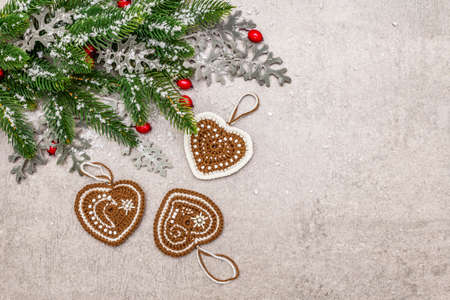 Christmas background. New Year fir tree, dog rose, fresh leaves, crocheted ginger cookies hearts and artificial snow. Stone concrete backdrop, copy space, top viewの写真素材