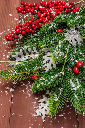 Christmas background. New Year fir tree, dog rose, fresh leaves and artificial snow. Wooden boards backdrop, close upの写真素材