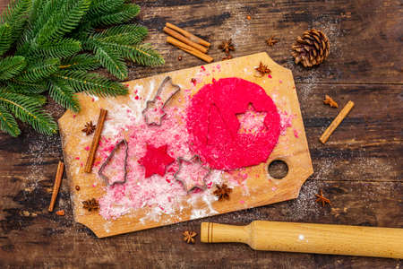 Cooking red ginger cookies. Traditional Christmas pastries. Festive culinary background. Fir tree, spices, cookie cutters, raw dough, rolling pin, wooden boards, top viewの写真素材