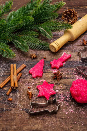 Cooking red ginger cookies. Traditional Christmas pastries. Festive culinary background. Fir tree, spices, cookie cutters, raw dough, rolling pin, wooden boards, close upの写真素材