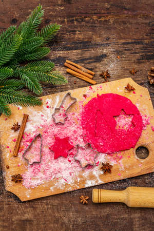 Cooking red ginger cookies. Traditional Christmas pastries. Festive culinary background. Fir tree, spices, cookie cutters, raw dough, rolling pin, wooden boards, top viewの写真素材